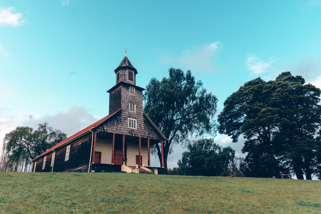 a small church with a steeple on a hill